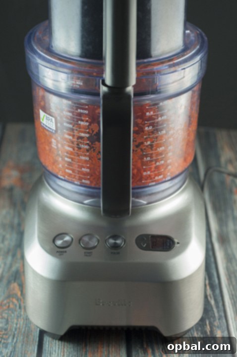 Fresh carrots being shredded in a Breville food processor for the cinnamon roll dough.
