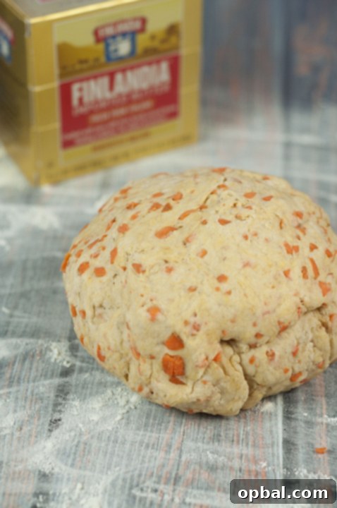 Carrot cake cinnamon roll dough rising in a bowl, covered with a damp cloth.