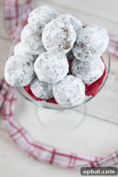 Festive No-Bake Rum Truffles 4 Three festive Christmas Rum Balls, glistening with powdered sugar, ready to be enjoyed