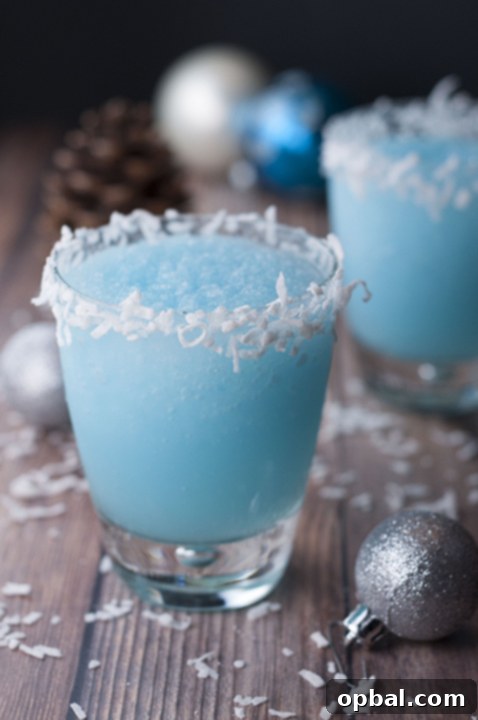 Arctic Blue Coconut Dream 2 Vibrant Blue Christmas Coconut Cocktail in a festive glass, garnished with coconut flakes, ready to bring holiday cheer.