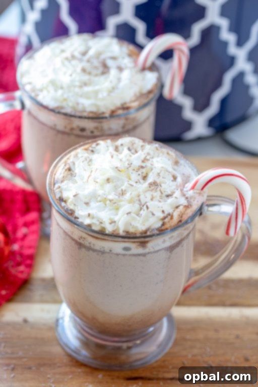 Cozy Slow Cooker Peppermint Mochas 5 A festive holiday table setup featuring mugs and garnishes next to a slow cooker filled with peppermint mocha, ready for guests.