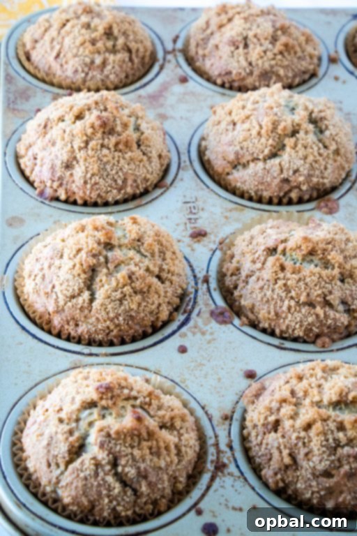Close-up of a stack of fluffy banana muffins, showcasing their rich brown sugar crumb topping.