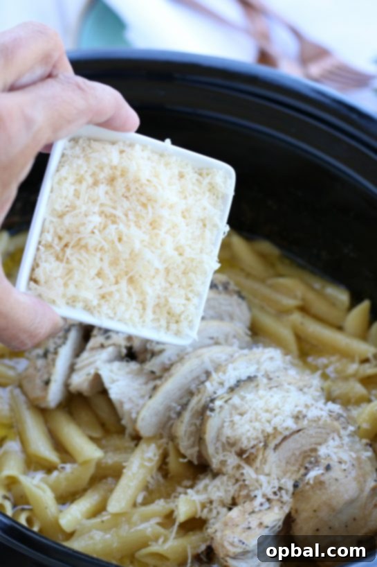 Slow Cooker Creamy Chicken Alfredo 10 Sprinkling freshly grated Parmesan cheese on top of a chicken alfredo crock pot recipe.