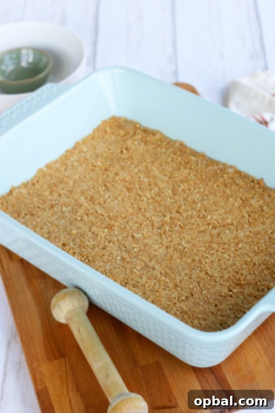 Pumpkin Spice Cheesecake Bars 6 A light blue colored baking dish perfectly prepared with the golden brown graham cracker crust for a cheesecake.