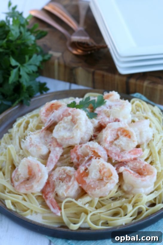 A beautifully composed image showcasing creamy garlic butter shrimp served over a bed of pasta, adorned with fresh herbs and a lemon wedge, highlighting its appeal as an easy and delicious dinner.