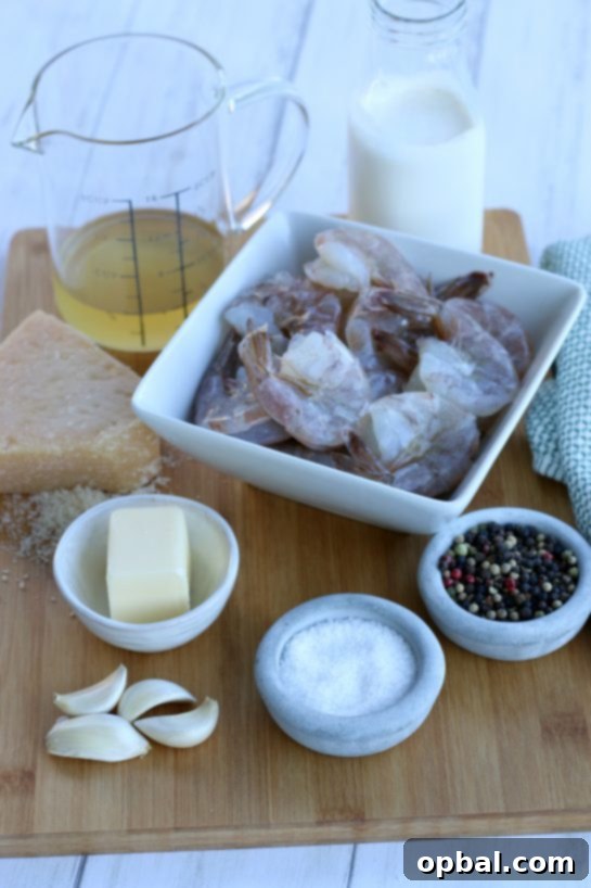 All the fresh ingredients laid out for making creamy garlic butter shrimp, including peeled shrimp, fresh garlic, butter, heavy cream, chicken broth, and Parmesan cheese.