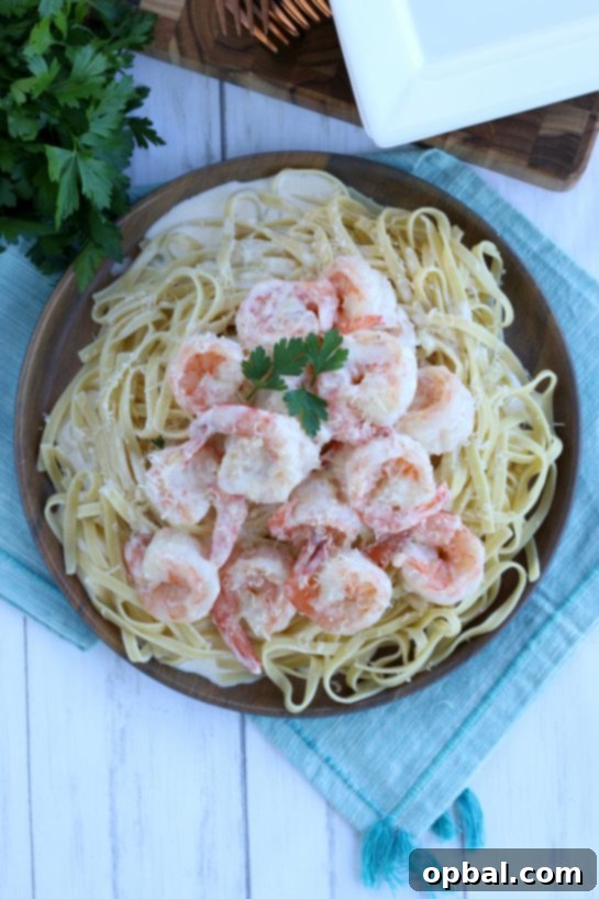 An overhead shot of a large platter filled with creamy garlic butter shrimp and pasta, garnished with fresh herbs, invitingly presented for a family-style dinner.