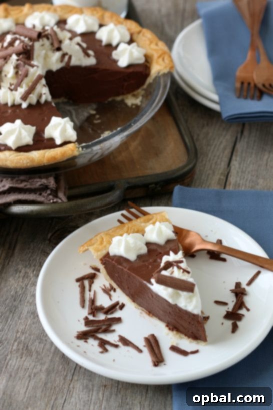 Decadent Chocolate Silk Pie 13 A perfect slice of homemade chocolate pie is served on a plate, adorned with a dollop of whipped cream, inviting everyone to savor its classic deliciousness.