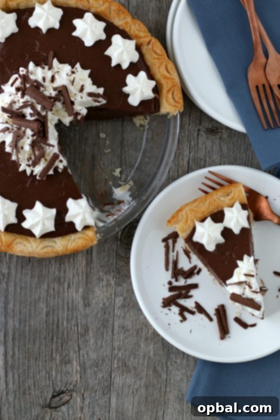 Decadent Chocolate Silk Pie 3 A delightful top-down view of the freshly baked homemade chocolate pie, with a perfect slice removed and served on a pristine white plate, showcasing its layers.