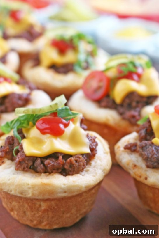 Cheeseburger Biscuit Poppers 2 A vibrant close-up shot of several freshly baked cheeseburger biscuit bites, topped with fresh shredded lettuce and diced pickles, ready to be enjoyed. Perfect for a Super Bowl party or a family dinner!