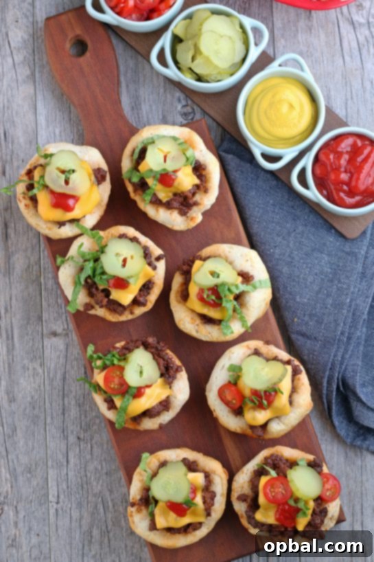 Cheeseburger Biscuit Poppers 4 A top-down view of a baking tray filled with perfectly golden-brown cheeseburger biscuit bites, each topped with a melted slice of American cheese, ready to be served hot.