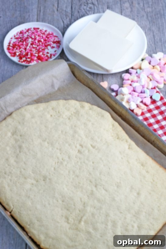 The cookie sheet is baked and ready to have toppings like icing and sprinkles added, preparing it for decoration!