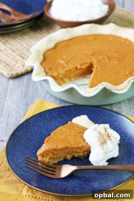 Velvet Sweet Potato Pie 3 A generous slice of the finished sweet potato pie on a white plate, topped with a dollop of fluffy spiced whipped cream, ready to be enjoyed.