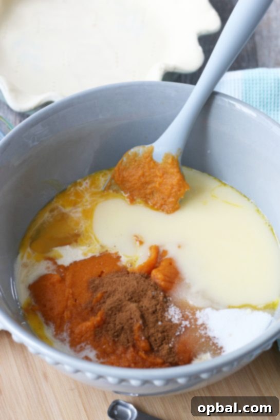 Velvet Sweet Potato Pie 5 The various ingredients for sweet potato pie are being poured into a large mixing bowl, ready to be combined.