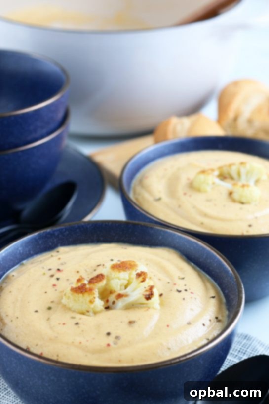 A beautifully plated bowl of creamy roasted cauliflower soup, garnished with crispy roasted cauliflower pieces and fresh herbs, ready to be enjoyed.
