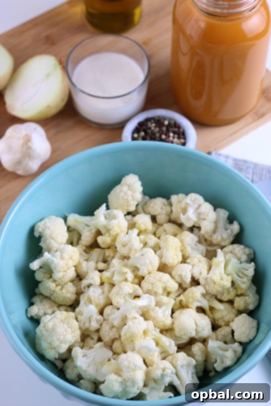 Cauliflower florets arranged on a baking sheet, glistening with olive oil and ready for roasting to achieve perfect tenderness and caramelization for the soup.