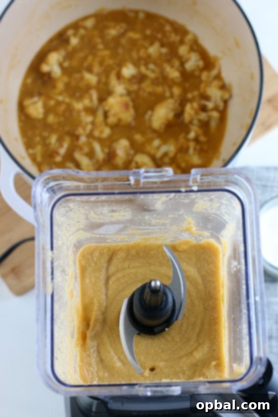 The smooth, creamy texture of the roasted cauliflower soup as it blends inside a blender, showcasing its luxurious consistency.