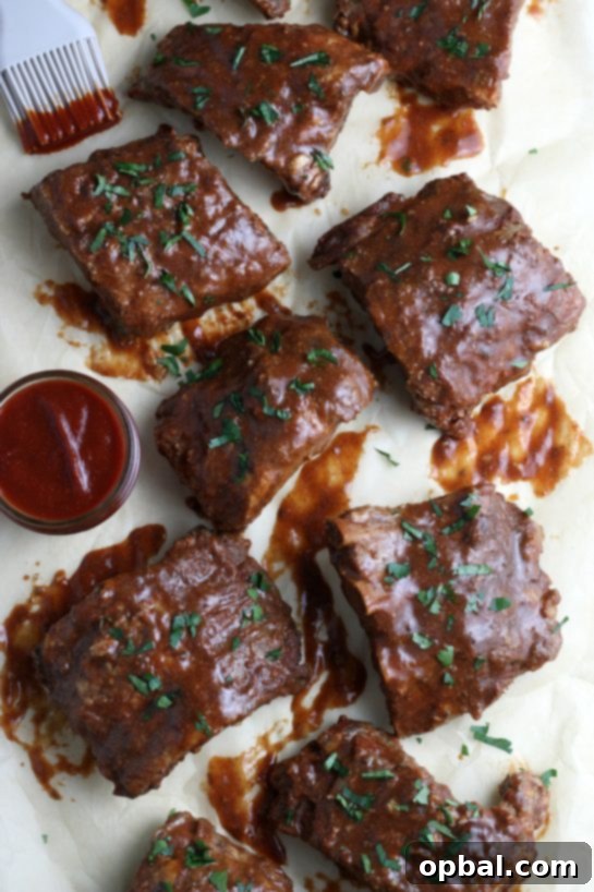 Fall-Off-The-Bone Slow Cooker BBQ Ribs 2 A top down view of perfectly cooked slow cooker ribs, glistening with a rich homemade BBQ sauce, garnished and ready to serve.