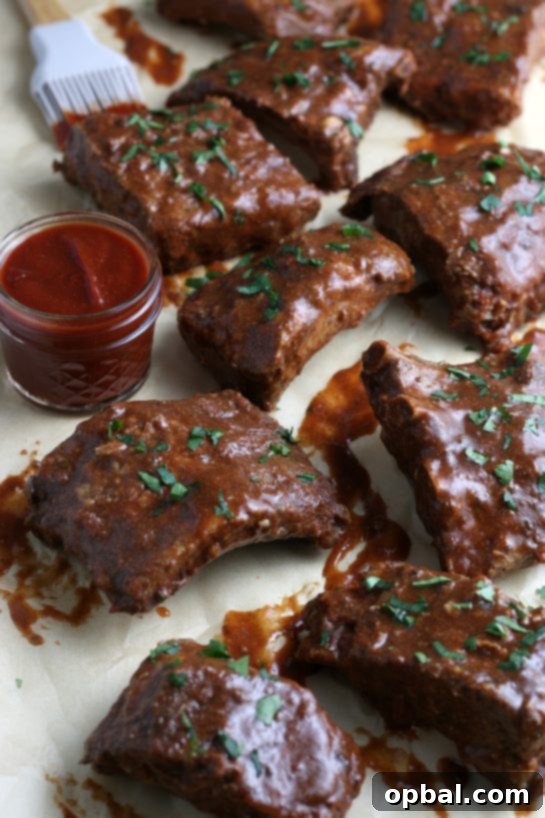 A vibrant close-up of the finished crock pot ribs, glistening with a generous coating of homemade barbecue sauce, promising deliciousness.