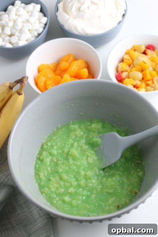 Pistachio Cloud Fruit Ambrosia 11 The glorious green color of the pistachio fluff mixture begins to form as the pudding mix and pineapple are combined.