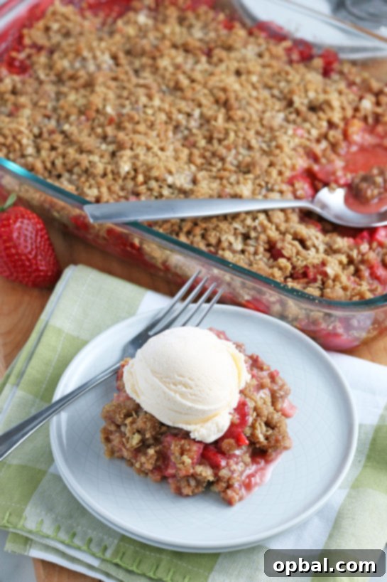 Delicious Strawberry and Rhubarb Crisp 2 Strawberry & Rhubarb crisp recipe finished in the pan and out of the oven and plated with a scoop of vanilla ice cream on top, ready to be enjoyed.