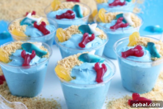 Seaside Pudding Parfaits 3 The cutest dessert recipe to make with kids: Beach Sand Pudding Cups, featuring vibrant blue pudding layered with sandy cookie crumbs and fun gummy candies.