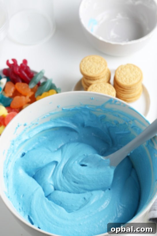 Seaside Pudding Parfaits 8 Carefully mixing together the blue pudding and whipped topping until fully combined and smooth, ensuring an even consistency for the Beach Sand Pudding Cups.