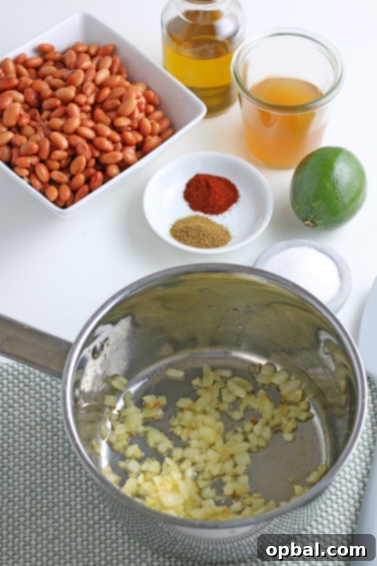 Sautéing diced onions until soft and translucent, the first step in creating flavorful refried beans