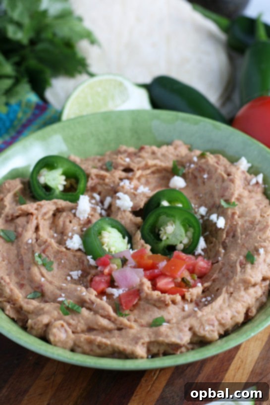 Platter of homemade refried beans garnished with fresh herbs, ready to be served as a restaurant-quality dish