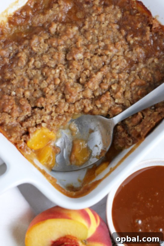 Sun-Kissed Peach Crumble 6 Scooping a generous portion of freshly baked peach crisp from the pan, highlighting its comforting layers and textures