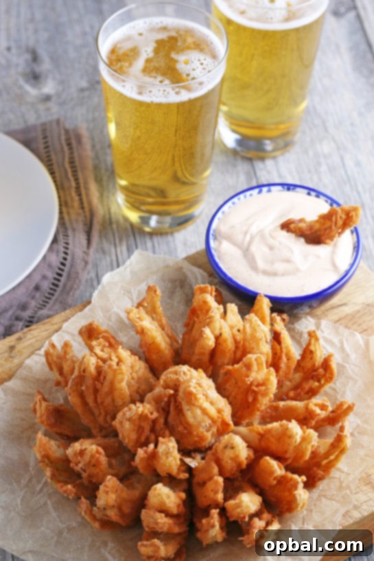 Golden Blossom Onion 2 Golden-brown Fried Blooming Onion with a creamy homemade dipping sauce, presented as the ultimate appetizer recipe. A sweet onion transformed into an incredible, delicious snack for game day!