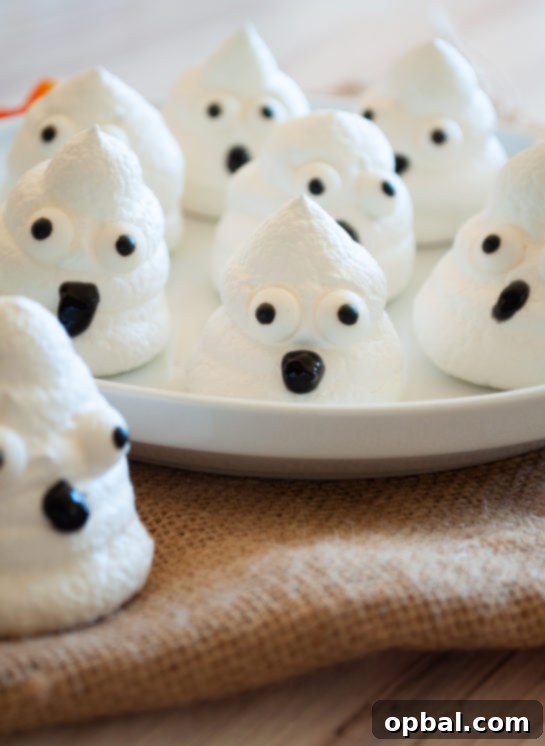 Spook-tacular Meringue Bites 11 A plate piled high with homemade Halloween Boo Meringues, a festive treat.