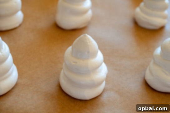 Spook-tacular Meringue Bites 7 Piping ghost shapes onto a baking sheet for Halloween Boo Meringues.