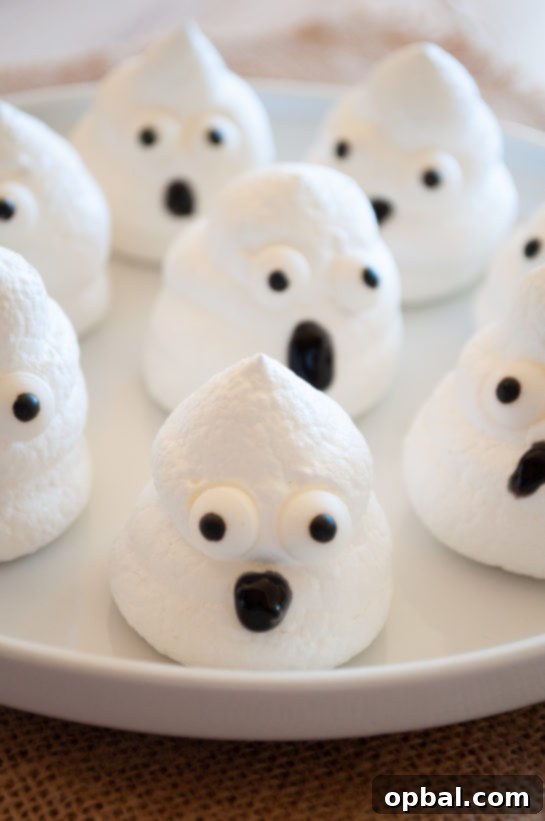 Spook-tacular Meringue Bites 8 Tray of baked Halloween Boo Meringues with playful candy eyes.