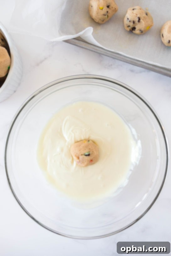 Decadent Dough Bites 16 Dipping an edible cookie dough bomb into smooth white chocolate glaze for a perfect coating