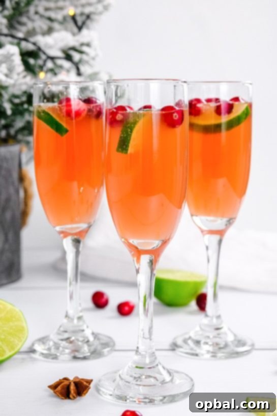 Festive Mimosas 7 A festive spread featuring several Holiday Mimosas, garnished with cranberries and lime, against a backdrop of holiday decor.