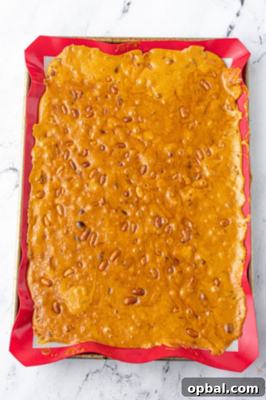 Quick Microwave Peanut Brittle 11 Spreading the mixture on the baking pan to make the Microwave Peanut Brittle recipe
