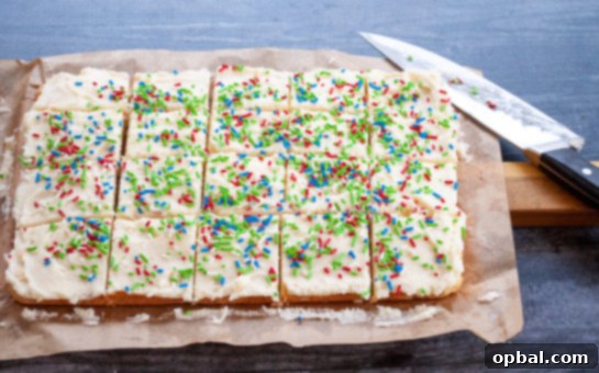 Sparkling Holiday Sugar Cookie Bars 3 Holiday Sugar Cookie Bars cut into squares and arranged on a white plate