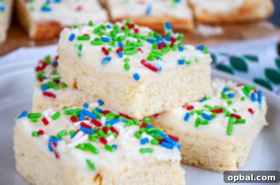 Sparkling Holiday Sugar Cookie Bars 8 Close-up of stacked Holiday Sugar Cookie Bars with festive sprinkles on a plate
