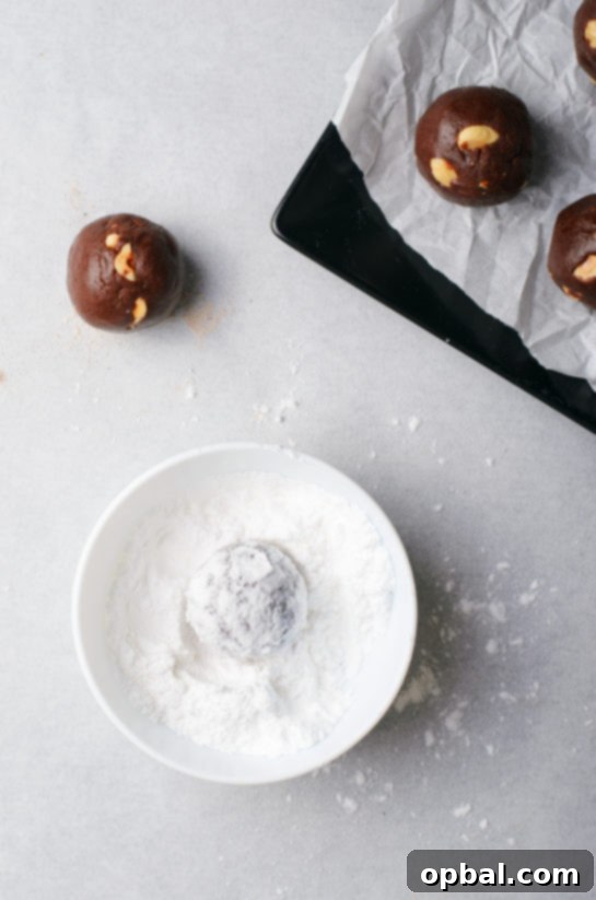 Rolling the cookies in powdered sugar for the chocolate hazelnut crinkle cookies recipe