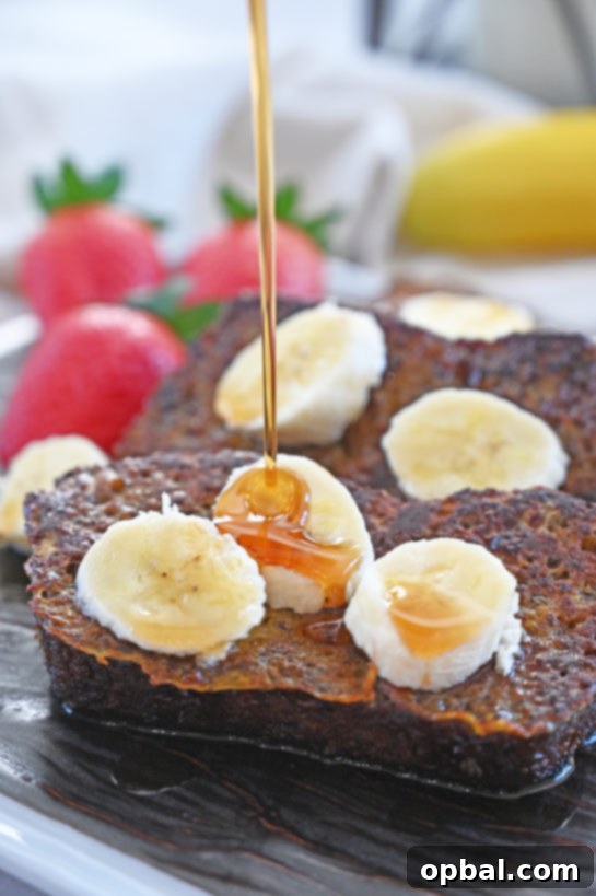 Golden-brown Banana Bread French Toast slices stacked with fresh banana and maple syrup.