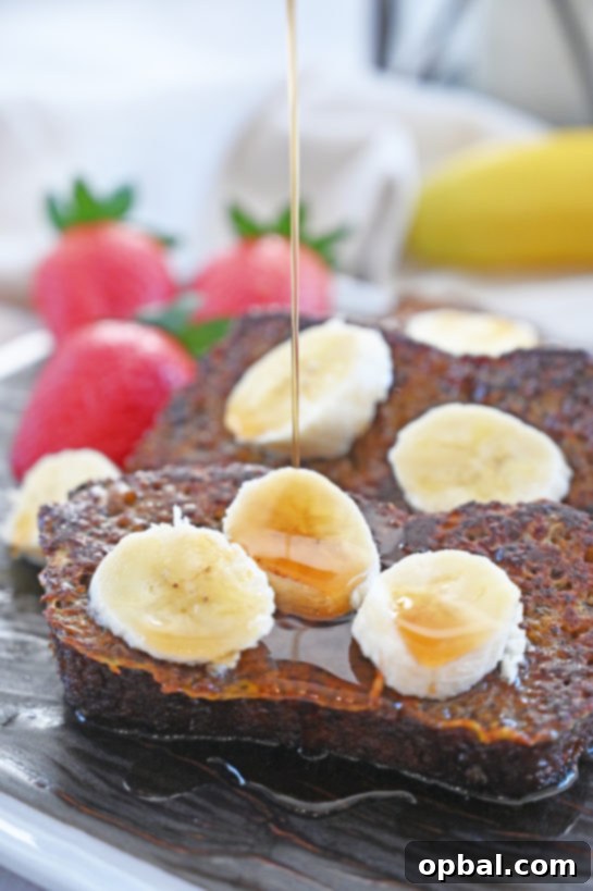 Ultimate Banana Bread French Toast 5 A stack of golden Banana Bread French Toast slices adorned with fresh bananas, powdered sugar, and a hint of lemon.