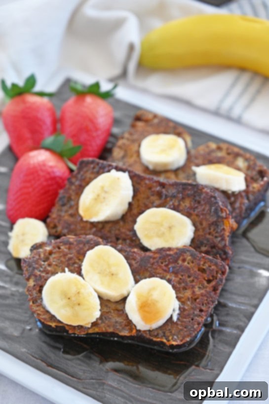 Ultimate Banana Bread French Toast 6 A stack of freshly made Banana Bread French Toast, garnished with banana slices and a light dusting of powdered sugar, ready to be served.