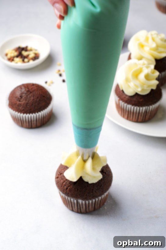 Velvet Chocolate Romance Cupcakes 7 Piping the vanilla cream cheese frosting onto the chocolate cupcakes