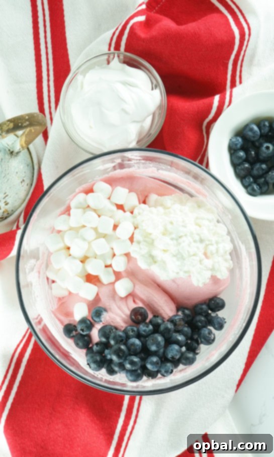 Stars and Stripes Fluff Bliss 5 Adding fresh blueberries and mini marshmallows to the creamy Jell-O and whipped cream base for the fluff salad.