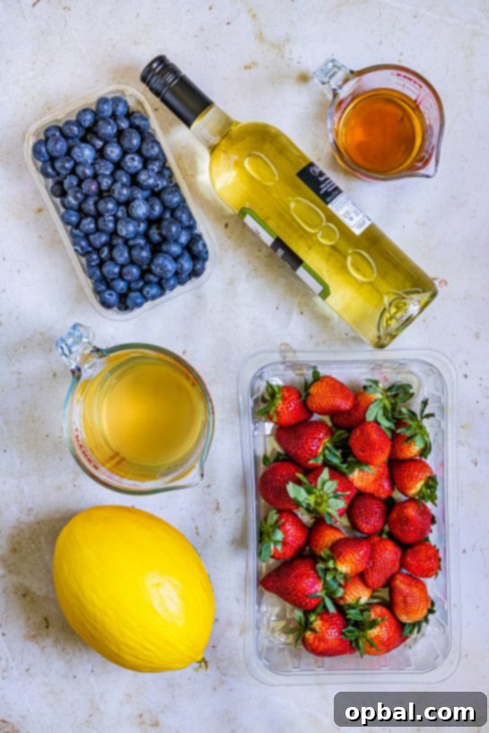 Freedom Sangria 3 Ingredients laid out for Patriotic Sangria, including fresh strawberries, blueberries, a whole honeydew melon, a bottle of white wine, brandy, and white grape juice.