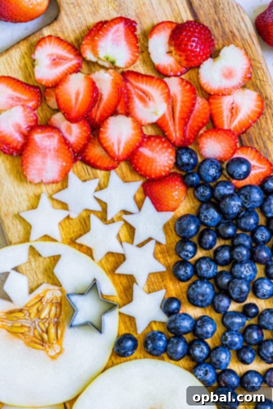 Freedom Sangria 4 Close-up view of fresh fruit, including sliced strawberries, whole blueberries, and star-shaped honeydew melon pieces, prepared for a patriotic sangria recipe.