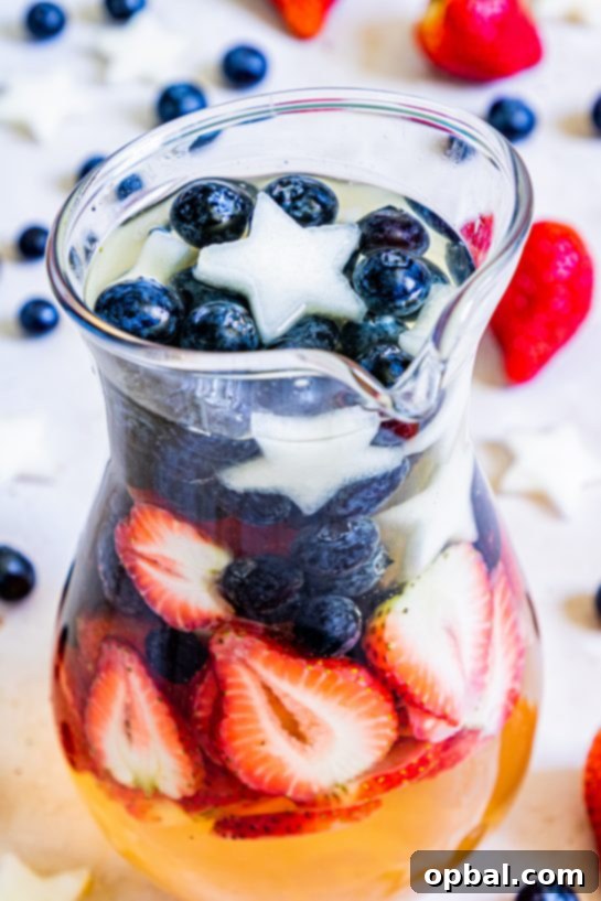 Freedom Sangria 5 A close-up shot of a glass filled with patriotic sangria, showcasing the vibrant red strawberries, blue blueberries, and white honeydew stars, ready to be enjoyed.