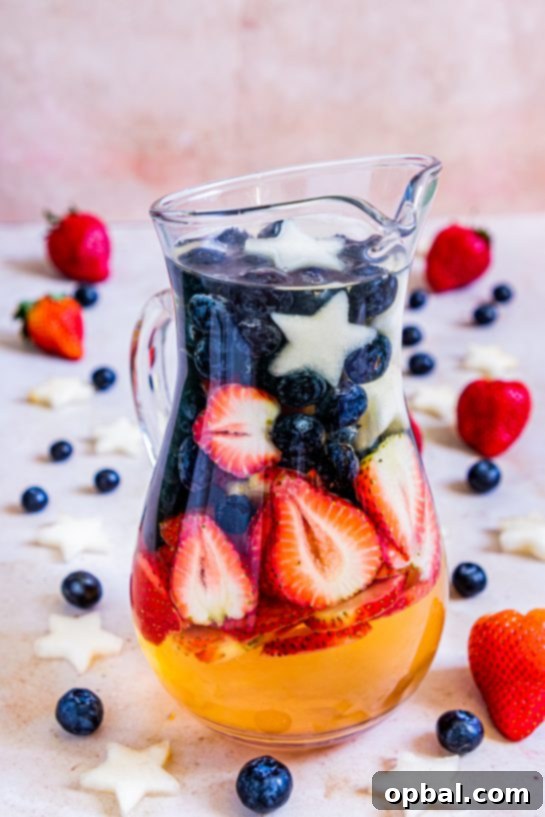 Freedom Sangria 9 A single glass of patriotic sangria filled with ice, berries, and melon stars, set against a bright background, perfect for a summer holiday.