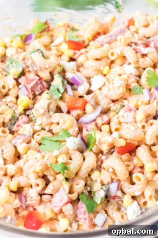 Elote Pasta Salad 7 Mixing all ingredients together thoroughly for the Mexican Street Corn Pasta Salad recipe, ensuring every piece is coated.